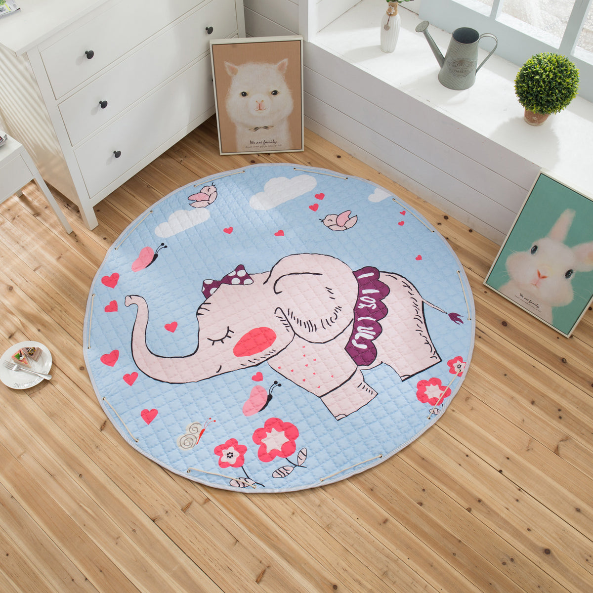 Round children's playmat with an elephant design on a wooden floor.