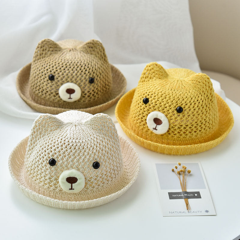 Three knitted bear hats in different colors on a white surface.