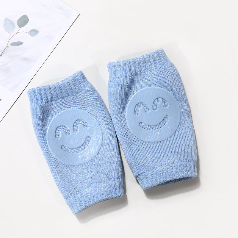 Pair of blue baby knee pads with smiley face design on a light background