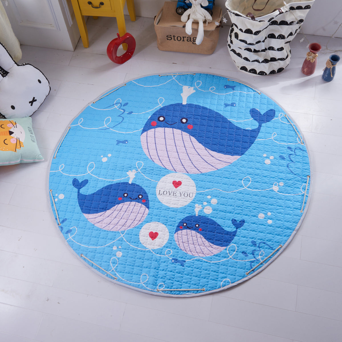 Round blue childrens play mat with whale design on a light gray floor.
