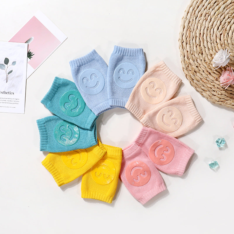 Set of colorful baby knee pads with smiley face designs on a light background.