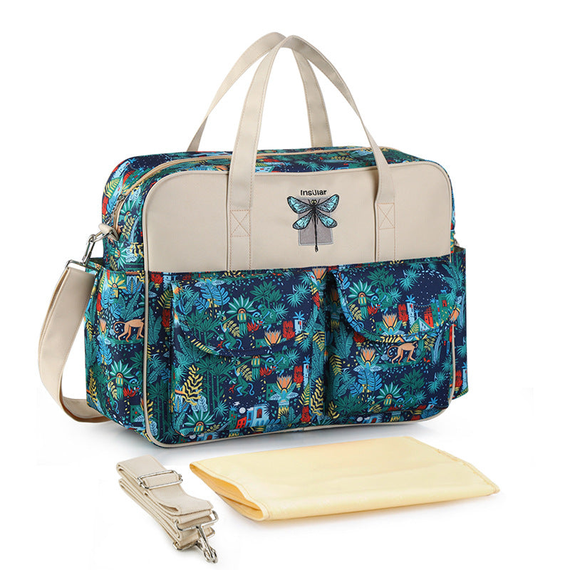 Multicolored patterned bag with beige accents and a butterfly design, accompanied by a matching strap and yellow blanket on a white background.