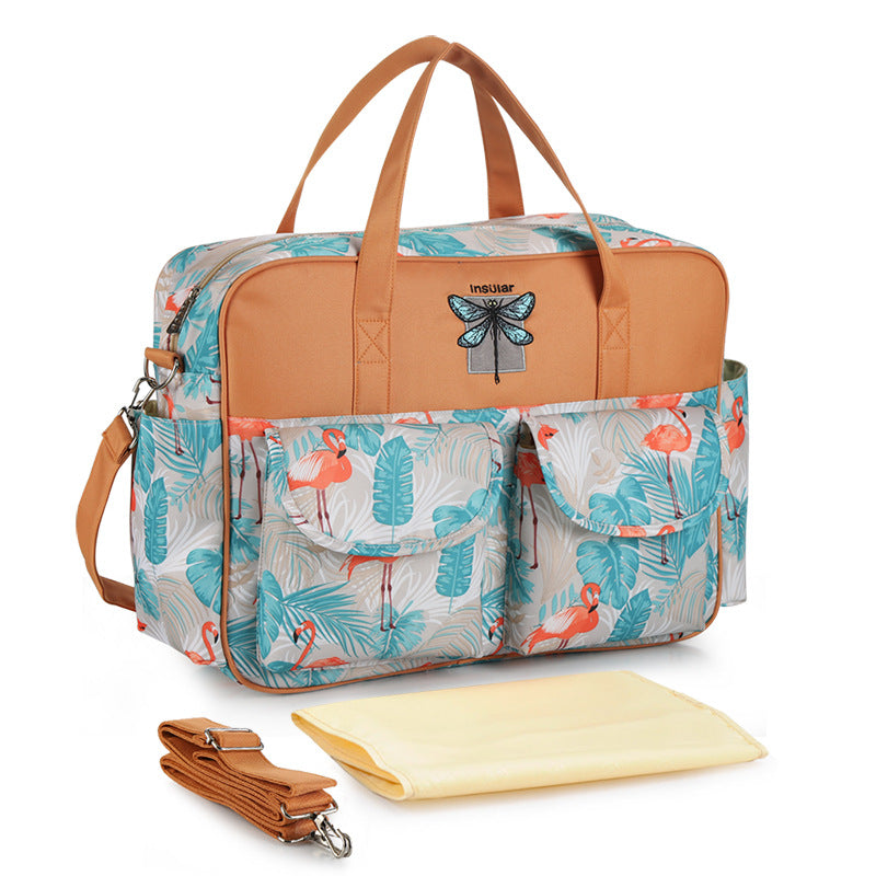 Floral-patterned diaper bag with brown accents and a matching strap on a white background