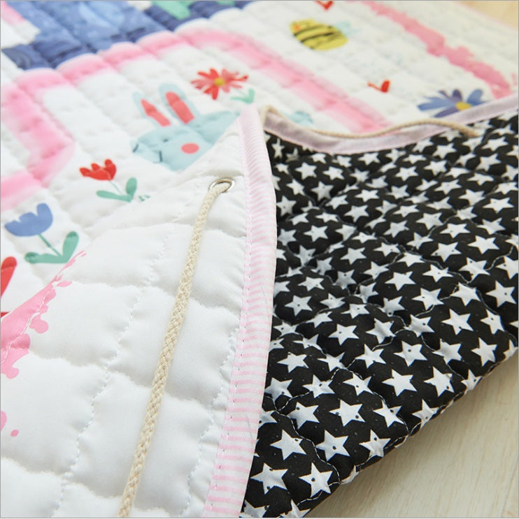 Close-up of a childrens playmat with colorful patterns on a wooden surface demonstrating the draw string mechanism