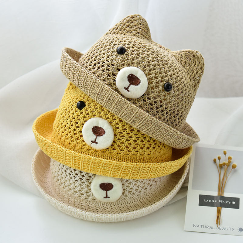 Stack of three knitted hats with bear face designs on a white surface.