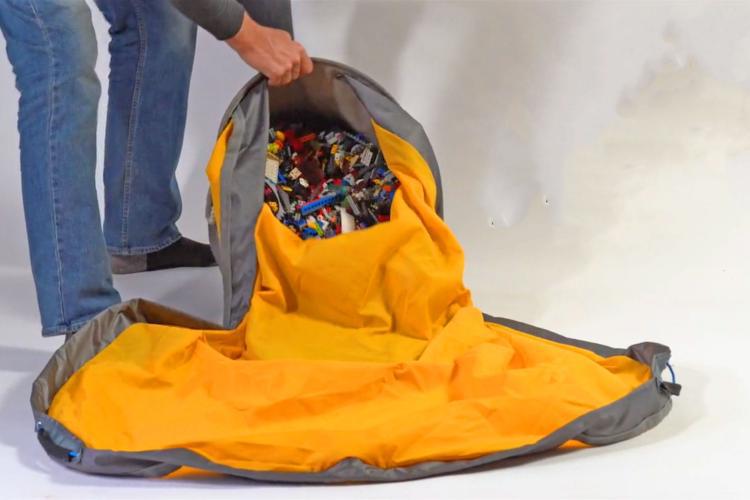 Person opening a large orange and gray bag filled with colorful items on a white background