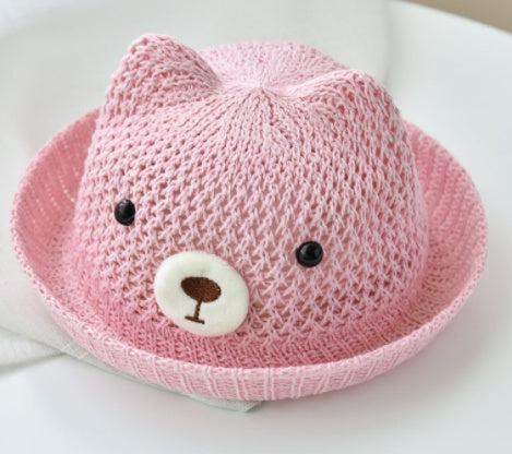 Pink knit hat with cat ears and a face on a white background