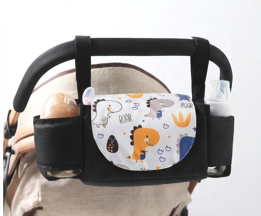 A black baby stroller accessory organizer with a central pouch featuring a colorful dinosaur pattern, holding baby bottles on either side.