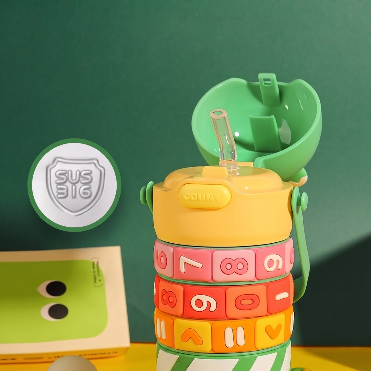A colorful children's water bottle with a green one-click lid and straw, shown with promotional text and a circular inset highlighting a food-grade silicone straw. The bottle has stacked number and letter segments in yellow, pink, orange, red, and green.