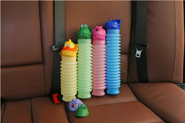 Set of colorful animal-themed emergency travel potty bottles in the back seat of a car