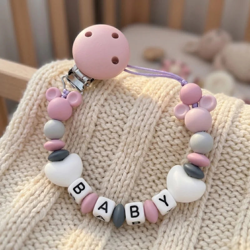 Baby teething necklace with colorful beads and 'BABY' letters on a textured surface.