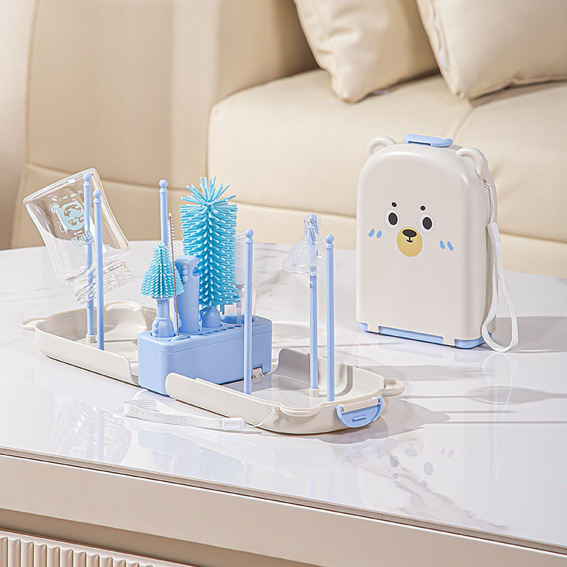 Set of blue baby bottle cleaning utensils and a white appliance with a bear design on a marble surface.