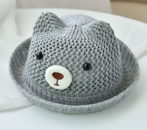 Gray knit hat with a face design on a white surface